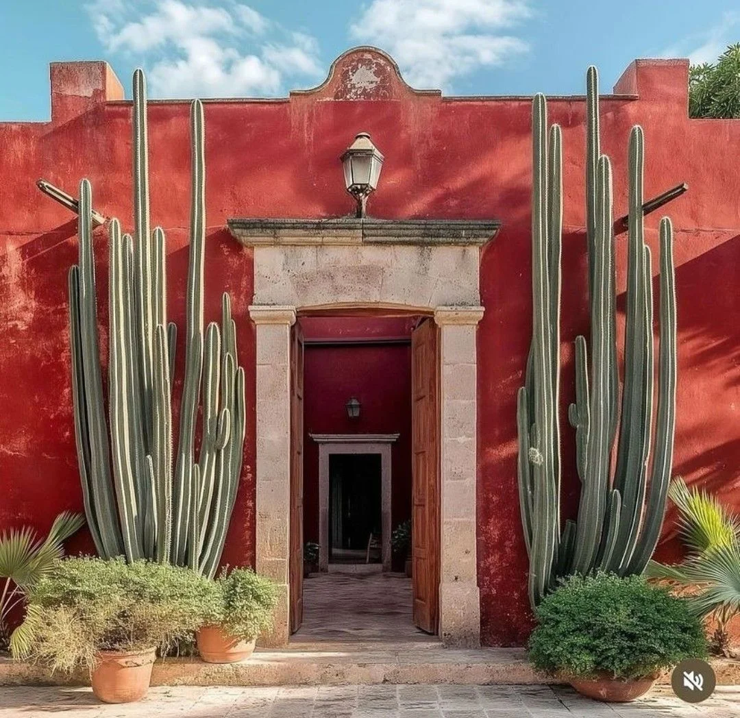 Red stucco entry framed by towering columnar cacti on either side